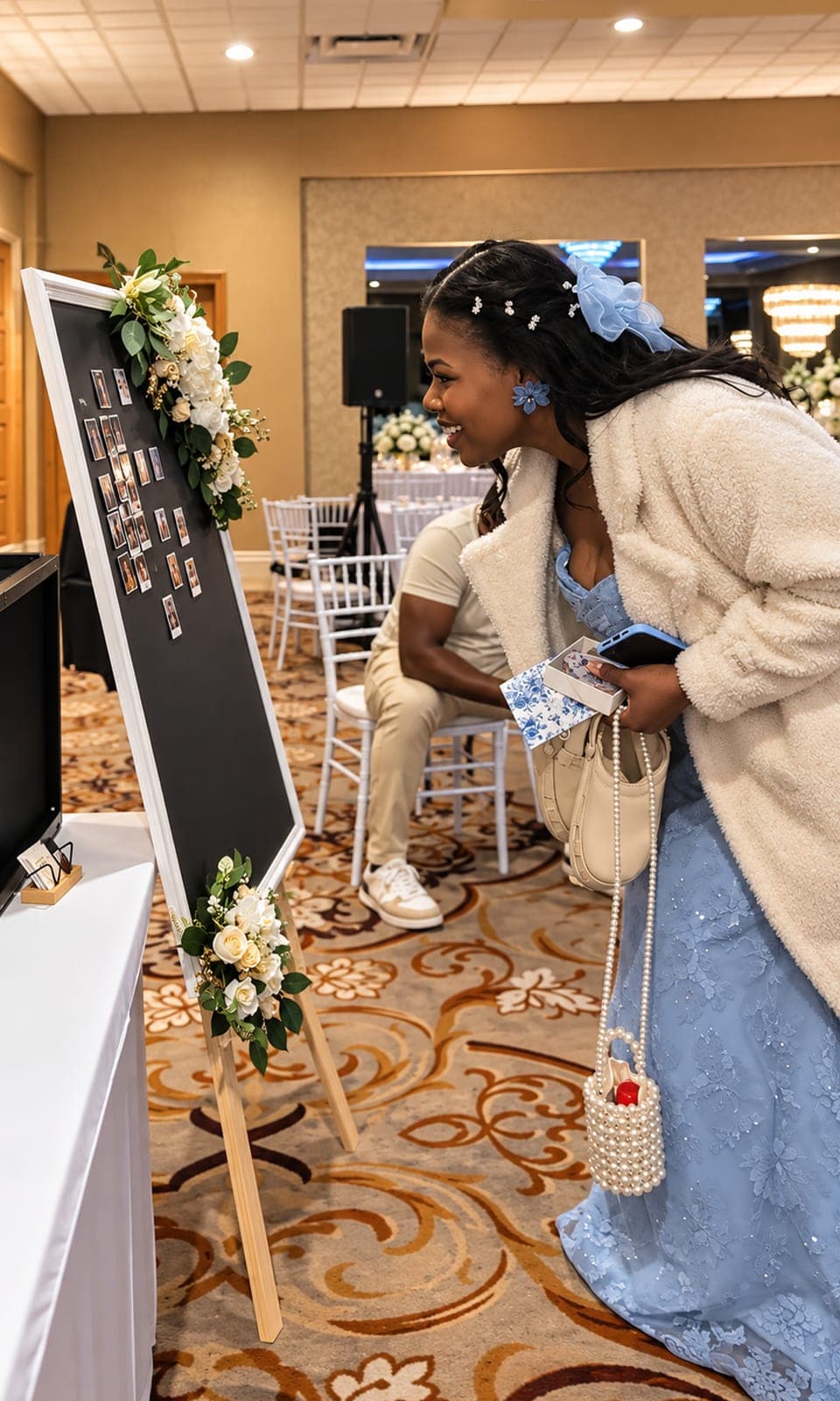 Smiling wedding guest in a blue dress looking at the photo magnets on the Memory Board